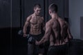 Bodybuilder, looking at himself, holding dumbbells Royalty Free Stock Photo