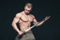 Bodybuilder man posing with a sword isolated on black background. Serious shirtless man demonstrating his mascular body Royalty Free Stock Photo