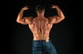Bodybuilder perfect shape rear view. Strong bodybuilder flexing arms muscles black background. Fit bodybuilder showing