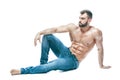 Bodybuilder posing. Beautiful sporty guy male power. Fitness muscled in blue jeans. on isolated white background. sits Royalty Free Stock Photo