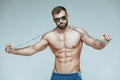 .bodybuilder posing. Beautiful sporty guy male power. Fitness muscled in blue shorts and sunglasses. on isolated grey Royalty Free Stock Photo