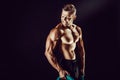 Bodybuilder posing. Fitness muscled man on dark background. Royalty Free Stock Photo