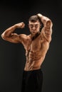 Bodybuilder posing. Fitness muscled man on dark background. Royalty Free Stock Photo