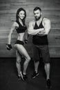 Bodybuilder with tattoo and beard and a smiling sporty girl are posing in a gym Royalty Free Stock Photo