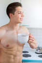 Bodybuilder young man daydreaming future shirtless drinking coffee in the kitchen portrait format Royalty Free Stock Photo