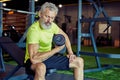 Bodybuilding in any age. Strong mature man in sportswear lifting heavy dumbbells and pumping his biceps while working