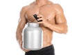 Bodybuilding and Sports theme: handsome strong bodybuilder holding a plastic jar with a dry protein and showing gesture isolated o