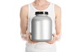 Bodybuilding and Sports theme: a thin man in a white T-shirt and jeans holding a plastic jar with a protein isolated on a white ba