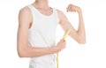 Bodybuilding and Sports theme: a thin man in a white T-shirt and jeans with measuring tape isolated on a white background in studi Royalty Free Stock Photo