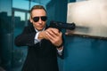 Bodyguard in suit and sunglasses with gun in hands