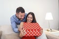 Bofriend surprising his girlfriemd with a gift. Young man giving a gift box to his girlfriend. Valentine`s Day and people concept Royalty Free Stock Photo