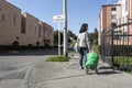 A Woman with face mask, gloves, market car and groceries in middle of lonely street of residential unit during obligatory quaranti