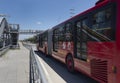 Peatonal Bridge of Transmilenio station with red bus and blue sky at background