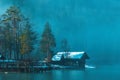 Bohinj lake boathouse at waterfront in foggy winter morning with wooden cabins and piers