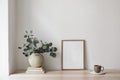 Boho breakfast still life. Cup of coffee, books. Empty wooden picture frame mockup on desk, table. Textured vase with Royalty Free Stock Photo