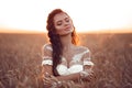 Boho chic style. Portrait of bohemian girl with white art posing over wheat field enjoying at sunset. Outdoors photo. Tranquility