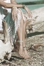 Boho girl wearing jewelry on feet and hands sit on  dried tree on the beach summer day close up Royalty Free Stock Photo