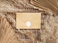 Boho sealed envelope on a wattled table with dry palm leaves and pampas grass Royalty Free Stock Photo