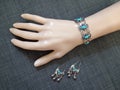 Boho style ethnic silver bracelet and earrings with turquose stones on mannequin hand