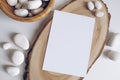 Boho vertical postcard mockup with white pebble and wooden cut section on white table background. Rustic bohemian image. Space for
