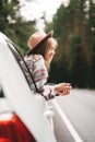 Boho woman sitting in car looking from window on beautiful view in country road