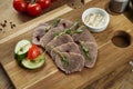 Boiled beef tongue with sauce and vegetables on a wooden board. Appetizing appetizer. Delicacy