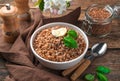 Boiled buckwheat with butter and basil on a brown background with buckwheat groats.