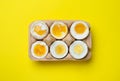 Boiled chicken eggs of different readiness stages in carton on yellow background, top view Royalty Free Stock Photo