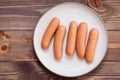 Boiled chicken sausages ready to eat on a plate on a wooden table