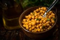 Boiled chickpeas in bowl with spoon, carafe with olive oil, herb in dark background Royalty Free Stock Photo