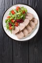 Boiled chopped beef tongue with fresh salad close-up in a plate. vertical top view