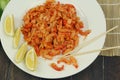 boiled craw fish meat on the plate with lemon slices, Japanese sticks, salad and straw mat closeup photo