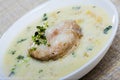 Boiled creamy soup with white fish pollock and greens at plate