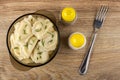 Boiled dumpling in brown bowl, shakers with pepper and salt, fork on table. Top view