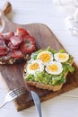 Hard boiled egg on avocado toast with green leaves and toast with fresh strawberries and cream cheese on wooden board, healthy bre Royalty Free Stock Photo