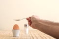 Boiled egg in an egg cup and a man`s hand holding a spoon Royalty Free Stock Photo