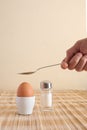 Boiled egg in an egg cup and a man`s hand holding a spoon Royalty Free Stock Photo