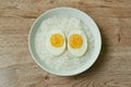 Boiled egg half cut topping rice porridge in white bowl on table Royalty Free Stock Photo