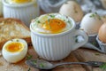 A boiled egg in a white cup with bread and a spoon on a wooden table, a closeup of half boiled eggs on the side. magritte sof Royalty Free Stock Photo