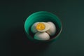 Boiled egg with yellow yolk with white eggs in green bowl on dark moody black plain minimal background, happy Easter d