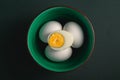 Boiled egg with yellow yolk with white eggs in green bowl on dark moody black plain minimal background, happy Easter day