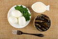 Boiled eggs and parsley in saucer, bowl with mayonnaise, opened jar with sprats, fork on mat. Top view