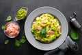 Boiled fettuccine pasta with fresh spinach pesto and shrimps on black background. Italian cuisine. Healthy dish for lunch Royalty Free Stock Photo