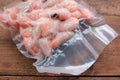 Boiled and frozen shrimps in vacuum transparent plastic packaging bag on wooden background. Royalty Free Stock Photo