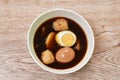 Boiled half cut egg with tofu in herb brown soup on bowl