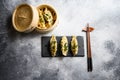 Boiled and hot chinese dumplings in wooden steamer and on black stone board slate over grey stone textured table background top Royalty Free Stock Photo