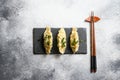 Boiled Japanese gyoza, dumplings snack  on black stone board slate with chopsticks  over grey stone textured table background top Royalty Free Stock Photo