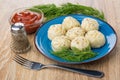 Boiled khinkali with dill in blue plate, ketchup, pepper