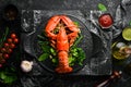 Boiled lobster with vegetables on a black stone plate. Seafood. Top view.