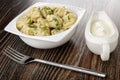 Meat dumplings with dill in white bowl, sauce boat with sour cream, fork on wooden table